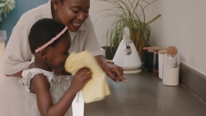 布，母亲和孩子打扫厨房柜台，帮助并高兴地在房子里打扫房间。家务，家务和非洲妈妈和一个女孩一起帮助清洁
