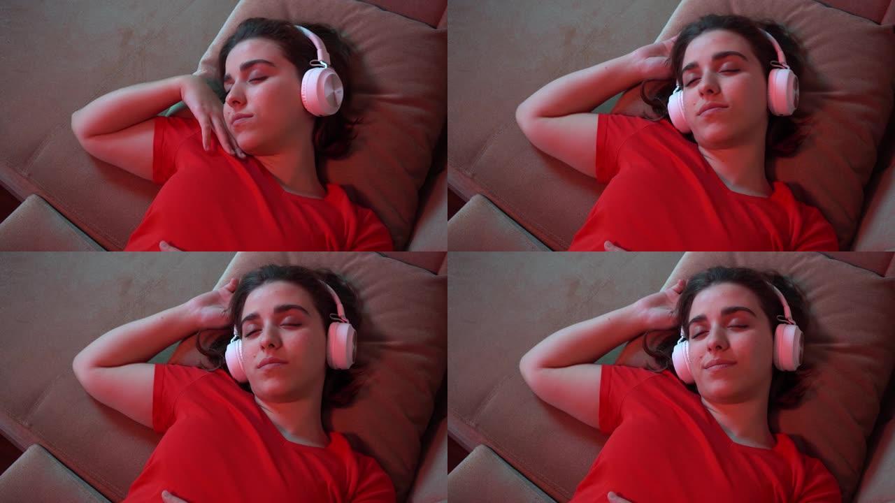 一个年轻女孩睡在她的棕色大沙发上。她正在听放松，放松，柔和的音乐。她戴着白色无线耳机。视频看起来很舒