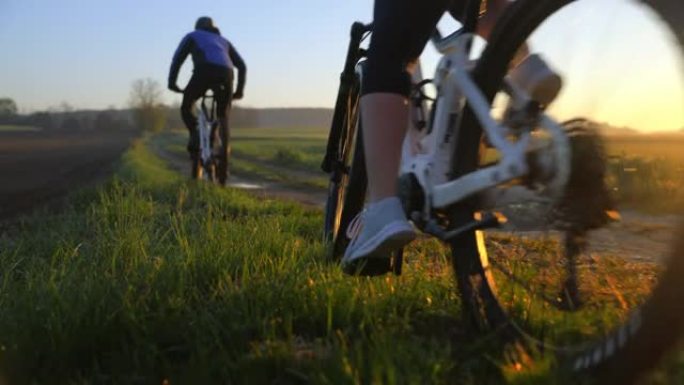 日落时分，SLO MO MTB骑自行车的人沿着乡村草地之间的小路骑行