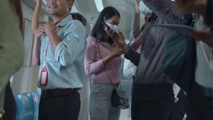 在社交距离和新常态之后的冠状病毒大流行期间，亚洲人在乘坐地铁地铁通勤上班时戴着手机口罩