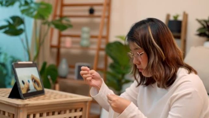 年轻的亚洲女性正在学习在线练习缝纫。