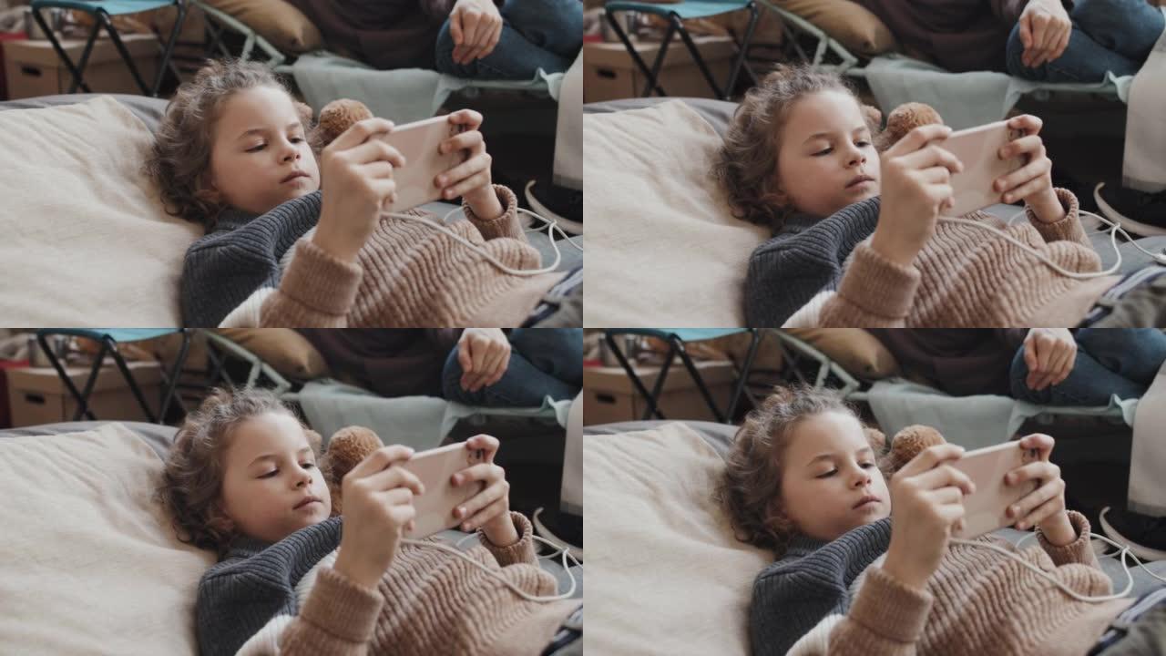 可爱的男孩在婴儿床上使用智能手机