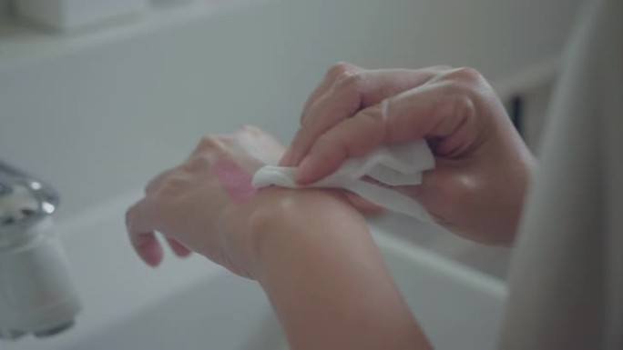 女人拿着湿巾用清洁剂清洁面部皮肤