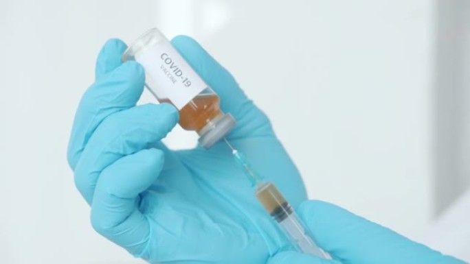 医院使用新型冠状病毒肺炎疫苗瓶和注射器的医用手套男性手特写