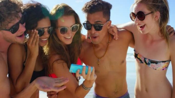 4k视频片段，一群不同的朋友一起站在海滩上并在手机上自拍
