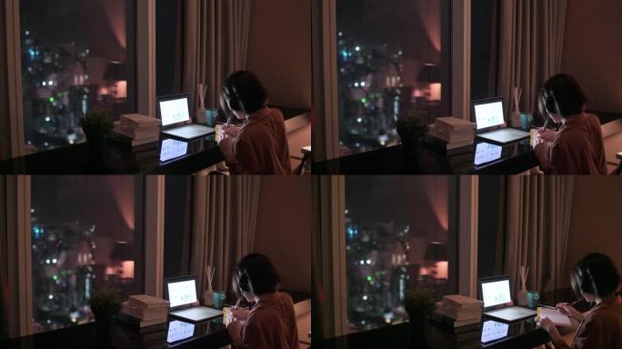 亚洲中国美女在书房使用笔记本电脑在家工作书写耳机