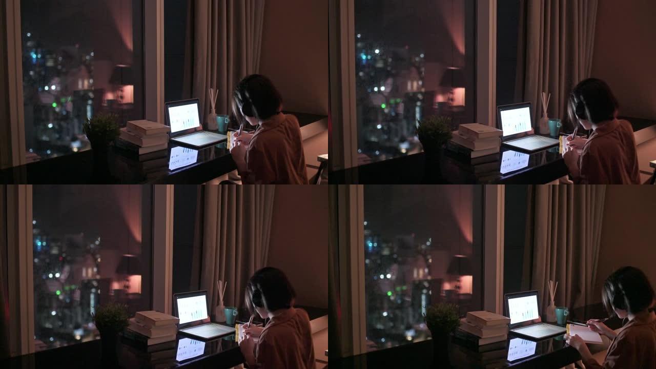 亚洲中国美女在书房使用笔记本电脑在家工作书写耳机