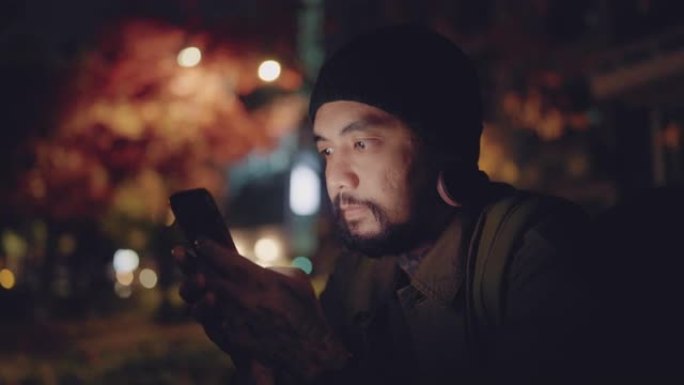 年轻的亚洲男子在公园休息时上网发短信。