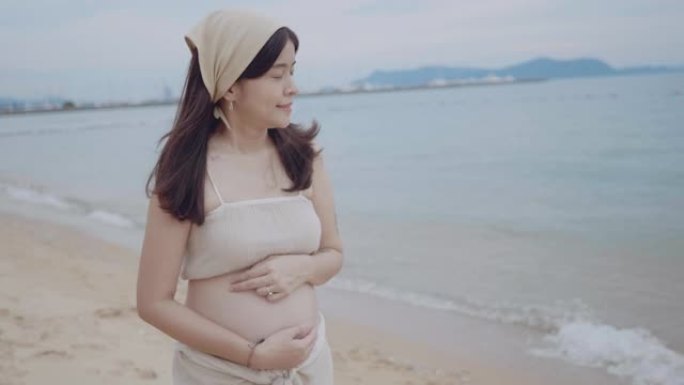 孕妇站在海滩上。抚摸洋孕妇微笑面部