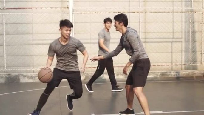 年轻的亚洲男子在室外球场上打篮球