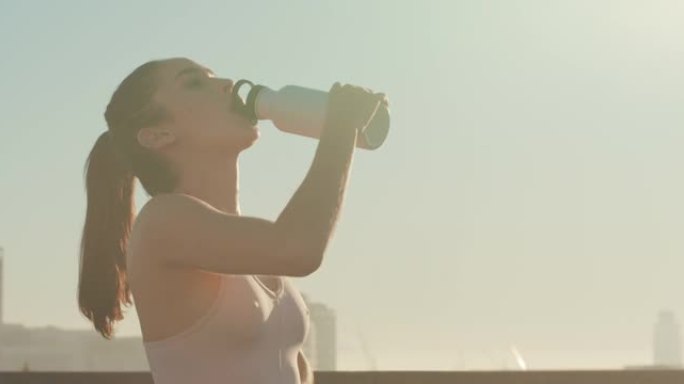 4k视频片段，一名年轻女子在跑步时喝了一瓶水