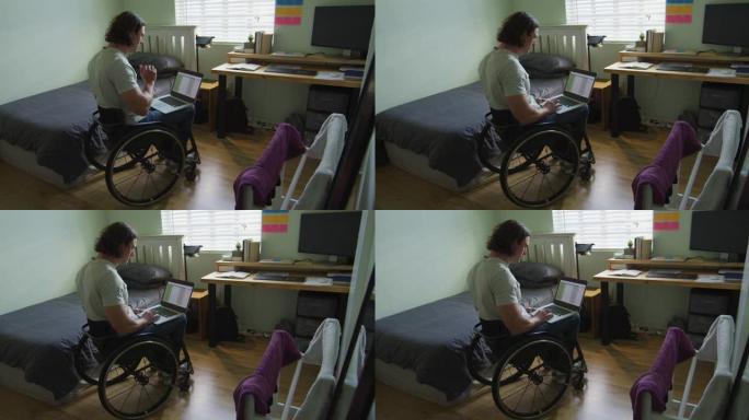 专注的高加索残疾人在卧室里使用笔记本电脑坐在轮椅上