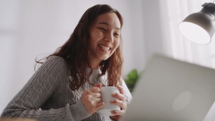 亚洲妇女看着笔记本电脑感到高兴