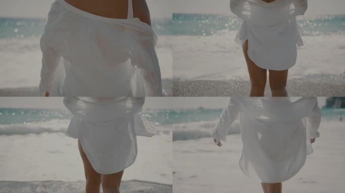 穿着白衬衫的SLO MO无法辨认的女人在海滩上散步