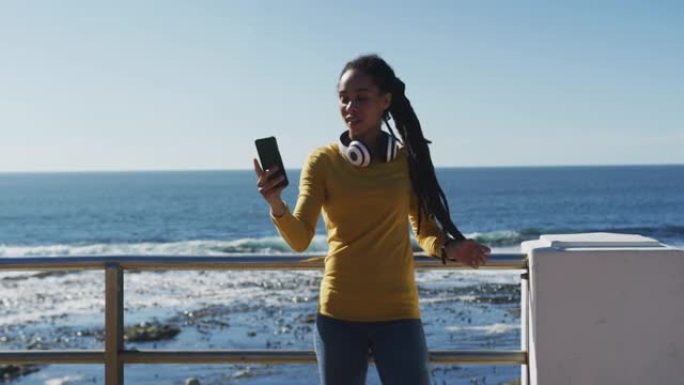 非裔美国妇女使用智能手机在海边的长廊上自拍