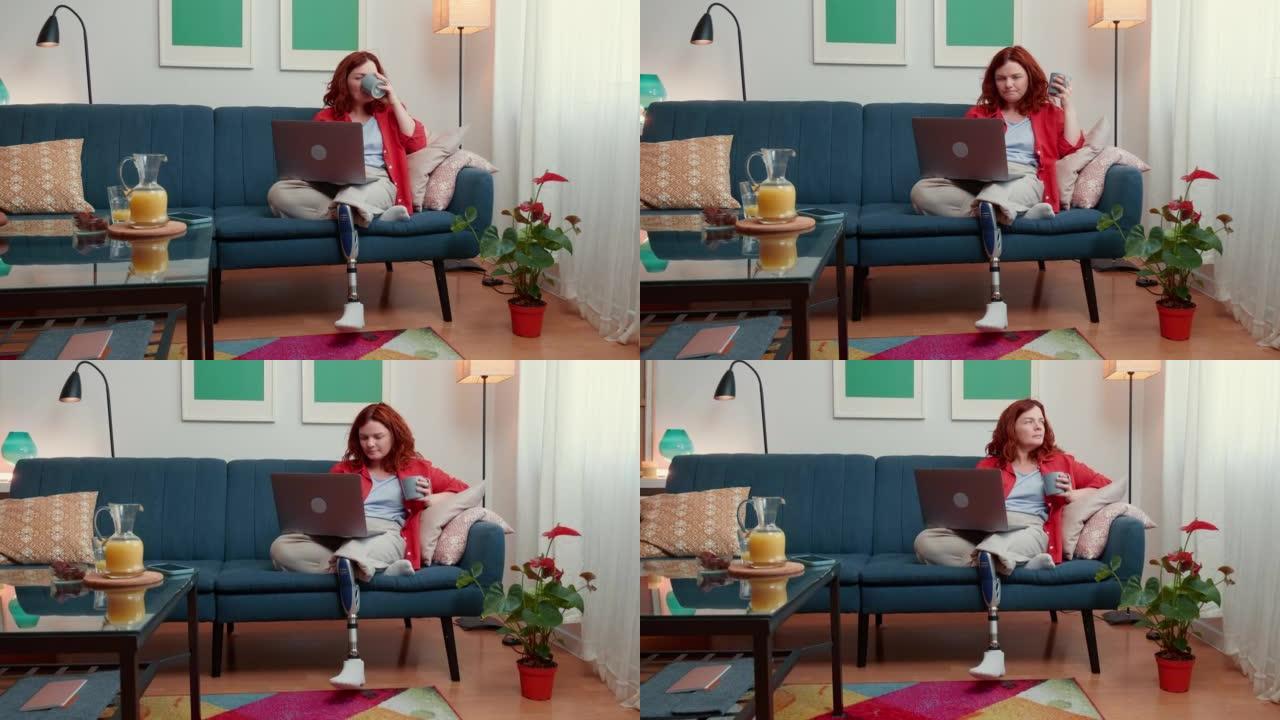 美丽自信的残疾女性博客作者，用笔记本电脑在家沙发上喝咖啡。