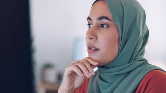 穆斯林女商人，面对和思考，阅读计算机屏幕并通过互联网连接打字报告。在印度尼西亚办公室工作的重点，研究