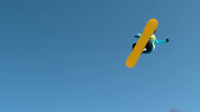 慢动作: 运动滑雪者跳到空中并执行抓斗技巧。