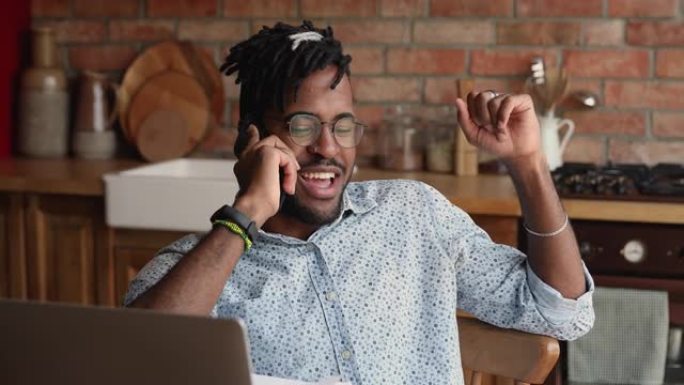 美国黑人男子远程工人使用笔记本电脑通过电话交谈