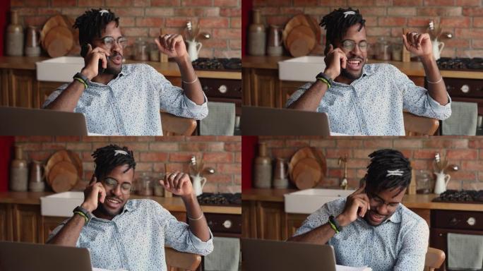 美国黑人男子远程工人使用笔记本电脑通过电话交谈