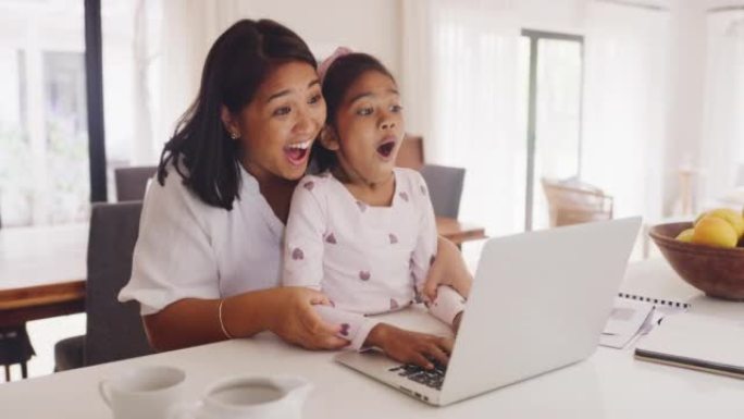 母亲和女儿在笔记本电脑上浏览并阅读好消息或看到惊人的东西时，看起来很惊讶，兴奋并说哇。上网时感到快乐