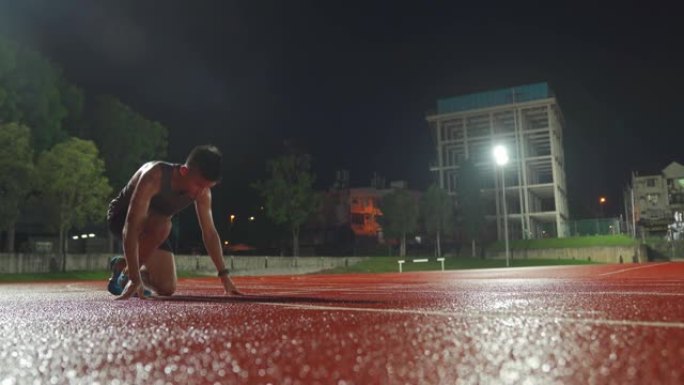 亚洲中国男运动员排队准备起跑线在男子田径雨天深夜在体育场跑步
