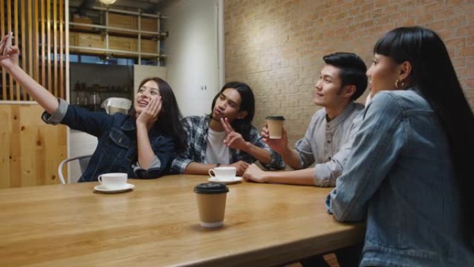 一群快乐的亚洲年轻人玩得开心，和她的朋友一起坐在咖啡馆餐厅自拍。