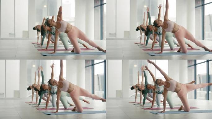 一群在瑜伽馆里伸展的女人。年轻的瑜伽士在普拉提课上锻炼。灵活的女性在运动垫上摆姿势。通过整体锻炼使人