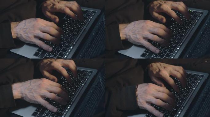 在笔记本电脑上打字的破旧连帽衫中粗糙的男性手的特写