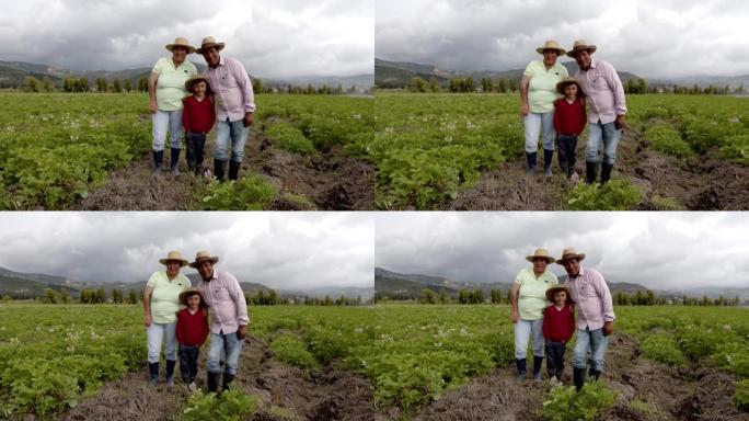 美丽的拉丁美洲农民家庭在马铃薯收割场站在一起，对着镜头微笑