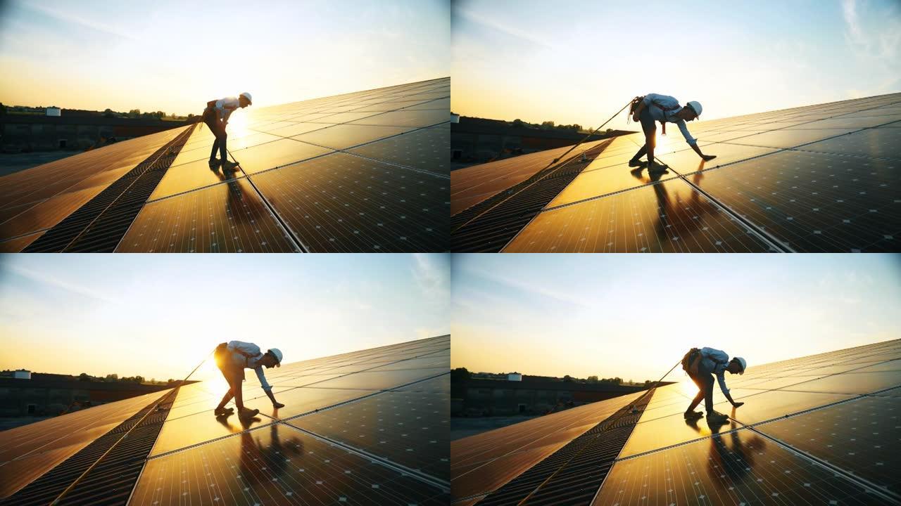 穿着制服的维修协助技术工人正在检查日落时屋顶上光伏太阳能电池板的运行和效率性能。前视图