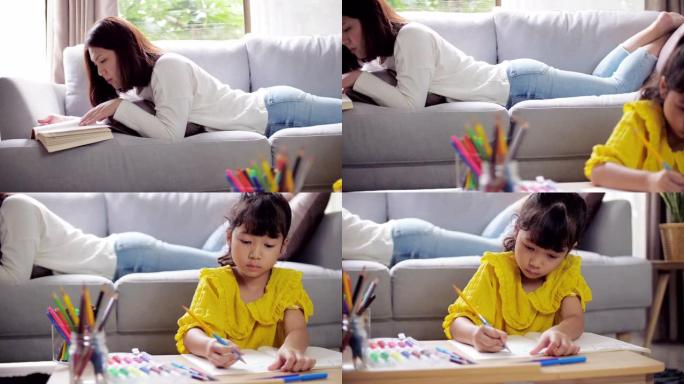 小女孩在家里的客厅里和妈妈一起看书，在放松的一天里做作业