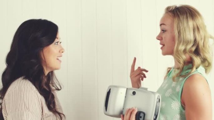 两名年轻妇女用即时相机互相拍照的4k录像