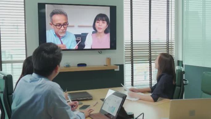 亚洲白领与公司员工进行视频会议在会议室讨论董事会与外国投资者进行视频通话。并购业务会议