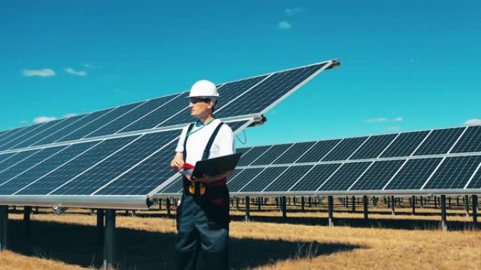 男工人正在观察一个太阳能发电场。现代太阳能电池板，生态友好型能源生产。
