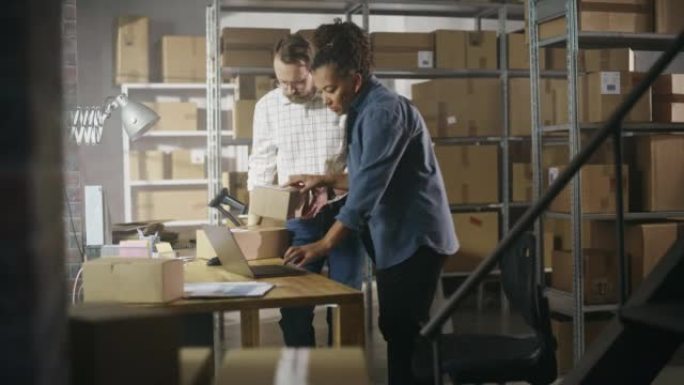 多样化的男性和女性仓库库存经理交谈，使用笔记本电脑并检查零售库存。背景中一排排装满纸箱包装的架子。