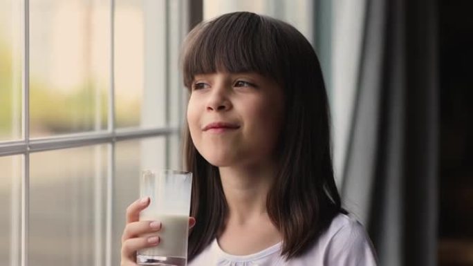 爆头肖像可爱的小女孩站在室内喝牛奶