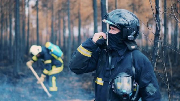 消防员正在充满烟雾的森林里通过收音机讲话