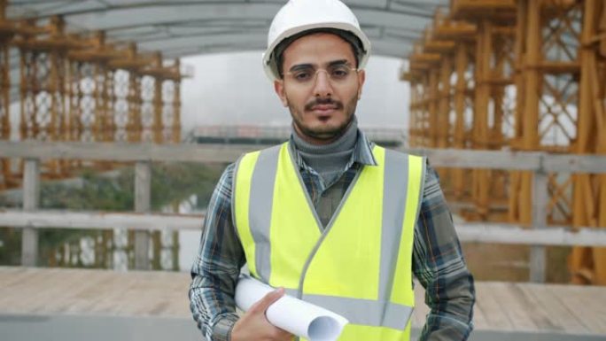 头盔中阿拉伯建筑专家的慢动作肖像站在建筑工地保持计划中