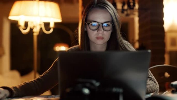 DS年轻女子晚上在笔记本电脑上工作