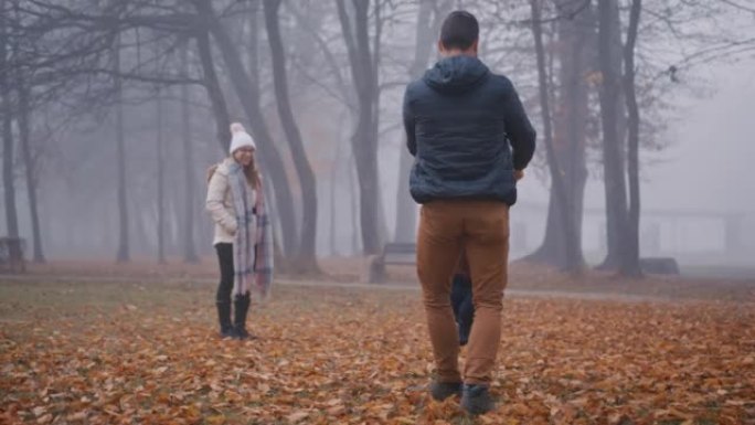 父亲在雾笼罩的秋天公园里旋转儿子