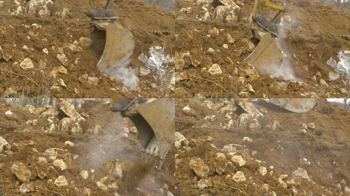 特写: 金属挖掘机铲斗铲起建筑工地附近的土壤和岩石