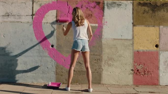 涂鸦艺术家女人画心形墙上粉色画叛逆的年轻女性享受和平与爱概念的艺术表达城市街头艺术4k