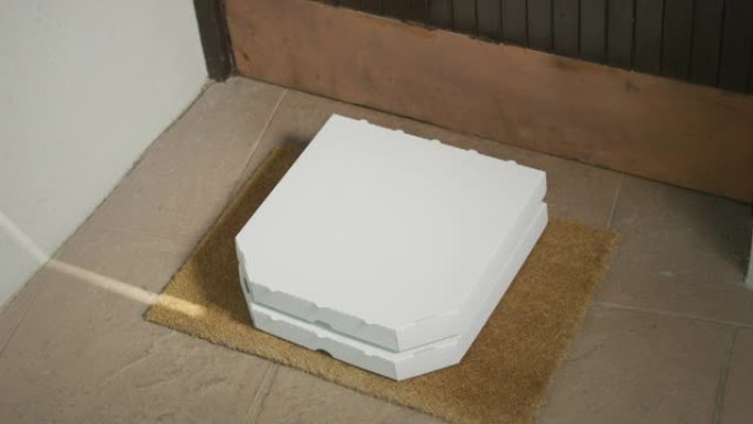 特写: 老年妇女拿起留在她家门口的两个纸板披萨盒。