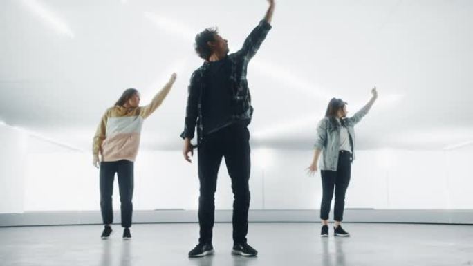 由三个不同的时尚专业舞者组成的小组，在大型Led墙壁屏幕前表演嘻哈舞蹈程序，并为工作室环境中的虚拟制
