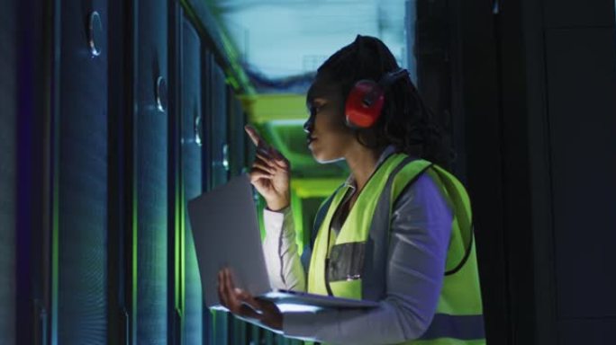 非裔美国女计算机技术员使用笔记本电脑在商务服务器机房工作