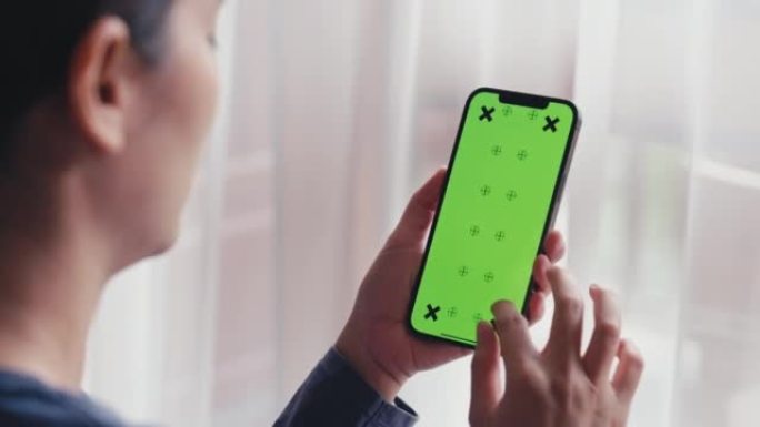 家中女性手中的绿屏模板智能手机特写镜头