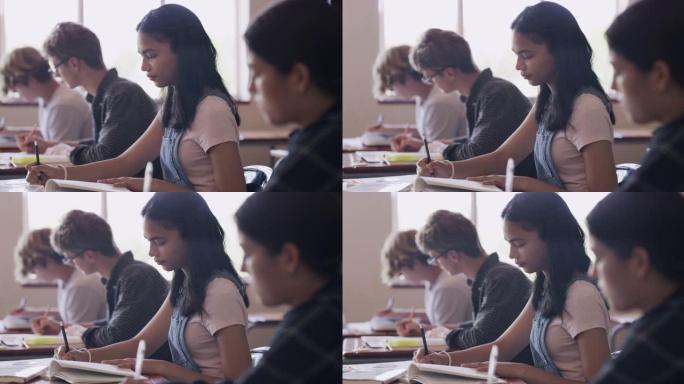 4k视频片段，一个十几岁的女孩在高中教室里的桌子上写字