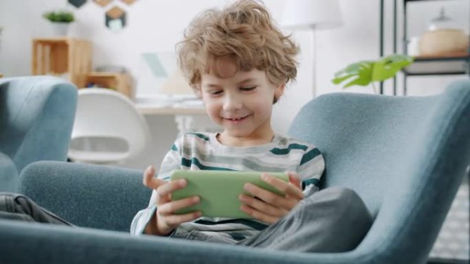 快乐的小男孩玩电子游戏在公寓里玩智能手机