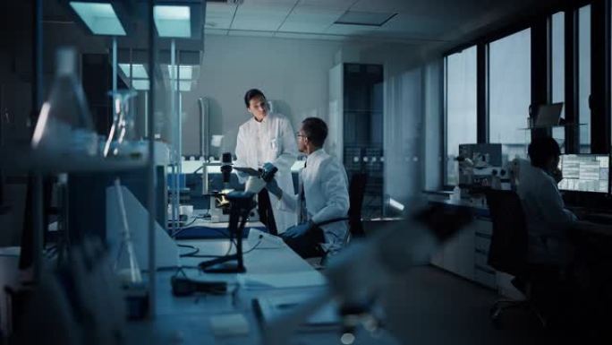 现代医学研究实验室: 两名科学家工作，使用数字平板电脑，分析测试，交谈。先进的医学科学制药实验室，生